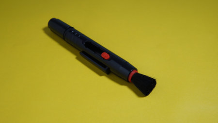 Black plastic brush on a yellow background. a brush for cleaning lenses and cameras on a yellow...