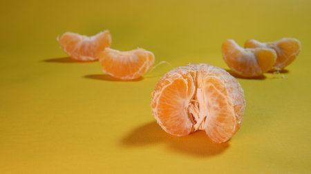 Peeled tangerine on a yellow background. Close-up. ripe orange fruit on a yellow backgroundの写真素材