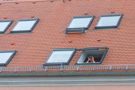Man looking with binoculars from the windowの写真素材