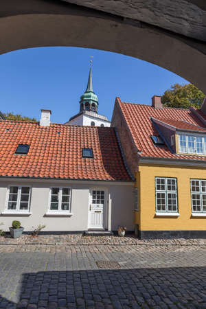 Looking through a passage on houses and a church spire