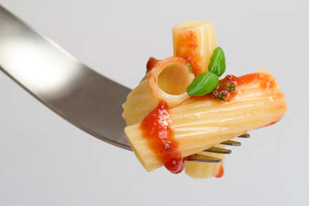 Rigatoni with basil and tomato sauce on a forkの写真素材