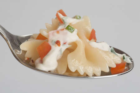 Farfalle with vegetables and cream sauce on a spoonの写真素材