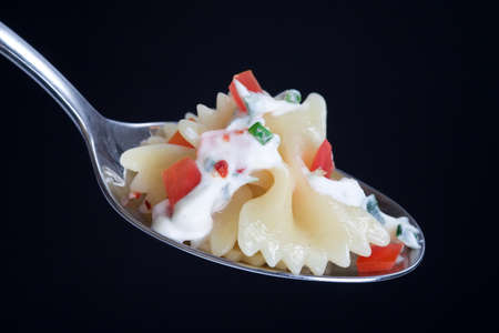 Farfalle with sauce and peppers on a tablespoon