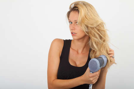 Young woman blow dries the blonde hairの写真素材