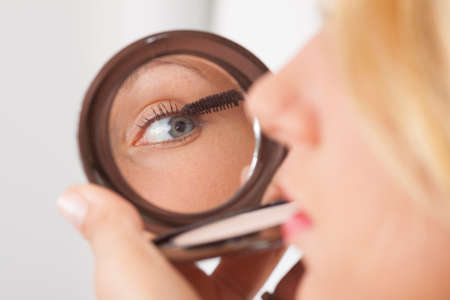 Young blonde in mascaras in the vanity mirrorの写真素材