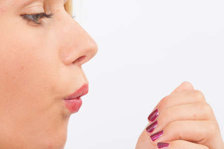 Young woman blowing on her fingernails for drying nail polishの写真素材