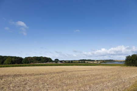 A picturesque lake surrounded by harvested fieldsの写真素材