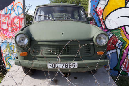 Green painted Trabant trapped in the wall and protected with barbed wireのeditorial素材