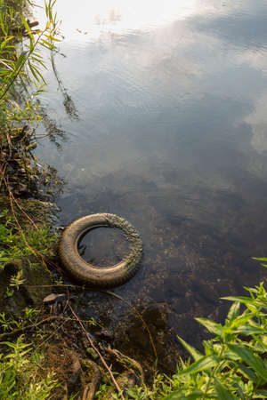 An old tire lies on the shore of a lakeの写真素材