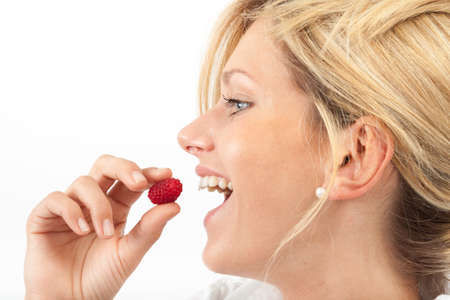 Young woman eating a single raspberryの写真素材