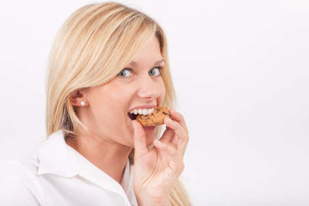 Young woman eating a chocolate chip cookieの写真素材
