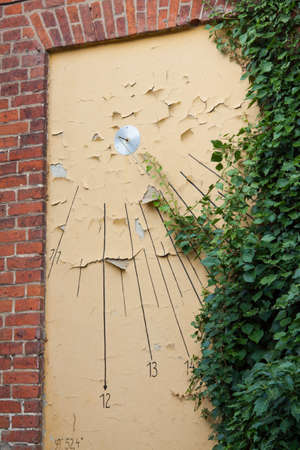 Sundial with flaking paint and ivy