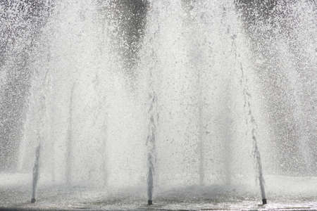 Water fountains in a fountain in backlightの写真素材