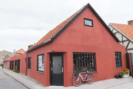 Red Corner House in Nykobing with a small shop and a bike in frontの写真素材