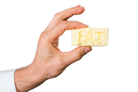 Close view of mans hand with a piece of butter with fat word on it.