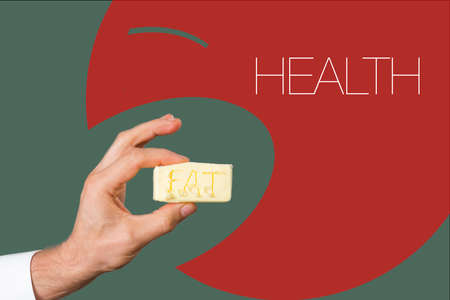 Close view of mans hand with a piece of butter with text FAT on it and big white text HEALTHの写真素材