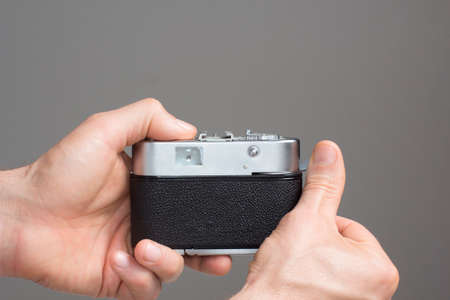 Close view of mens hands with vintage camera in a grey background