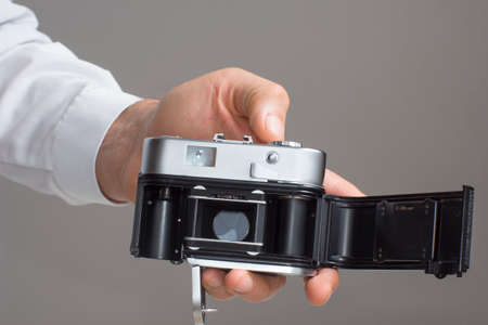 Close view of mens hand with vintage camera in a grey background