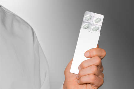 Mens hand with a white pills in a cardboard packet