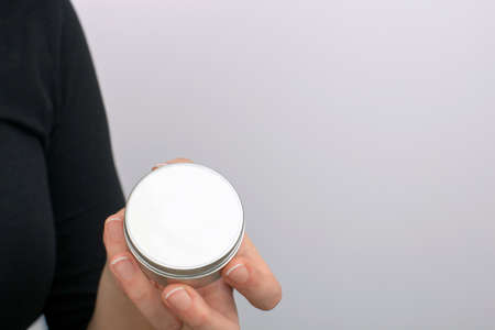 Close view of a girls hand with a small metalic box for a creamの写真素材