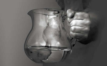 Close view of a mans hand with a pitcher of water in itの写真素材