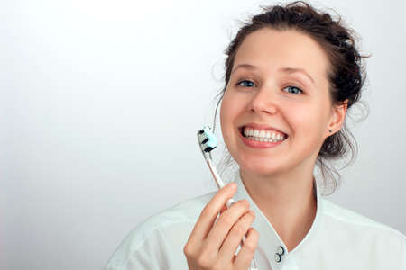 Portrait of a smiling girl with a big green red blue color toothbrush