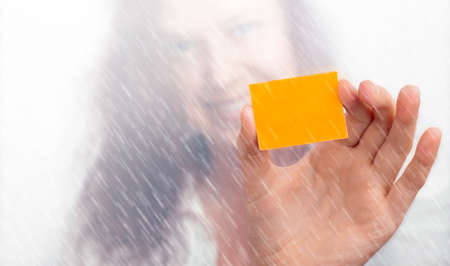 Girls hand with a yellow slip of paper in the rainの写真素材