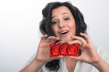 Smiling girl with  with three red condom packsの写真素材