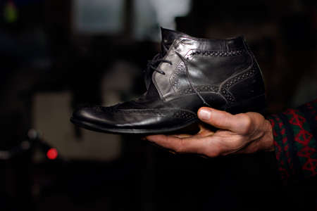 Close view of an old black shoe in an old mans handの写真素材