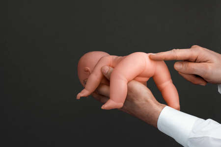 Mens hands with a baby doll in a dark backgroundの写真素材