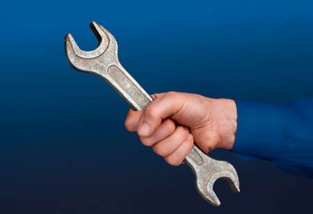 Close view of a males hand with a wrench in a blue background