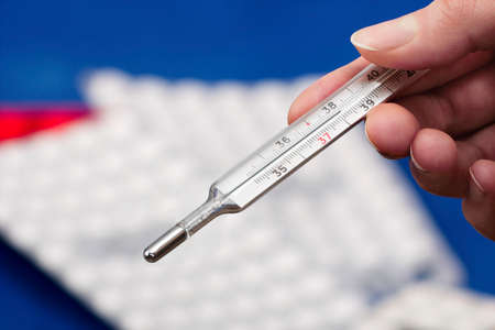 Medical mercury thermometer showing elevated body temperature in woman