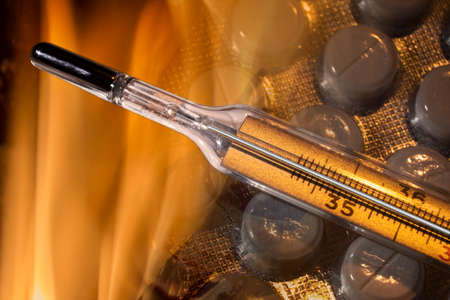 Mercury thermometer showing high tmperature and tablets in fire