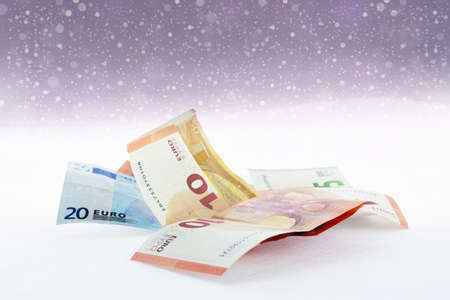 Falling snow and  euro banknotes in a bright warm backgroundの写真素材