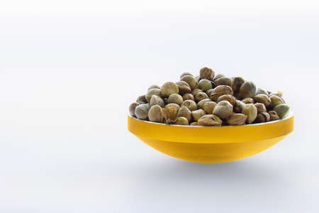 Hemp seeds in a gilded bowl in a white backgroundの写真素材