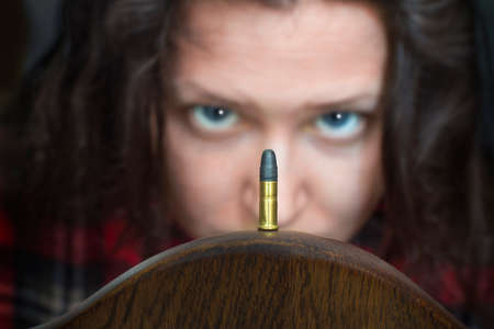 Woman looking at a guns bullet with a strange expression on her face.