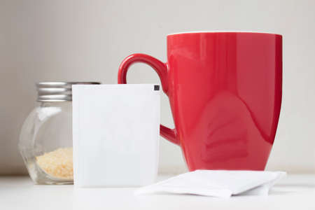 Close view of blank tea sachet with teabag red teacup and brown sugarの写真素材