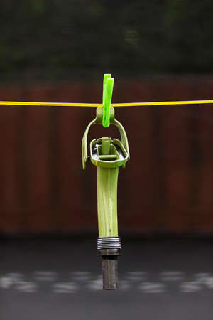 Metallic spout for can pinned with clip on a yellow rope
