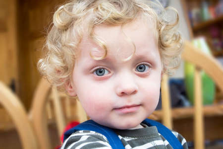 Pensive little boy  with golden curly hair