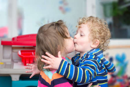 Little curly blond boy kiss a brunette  little girlの写真素材