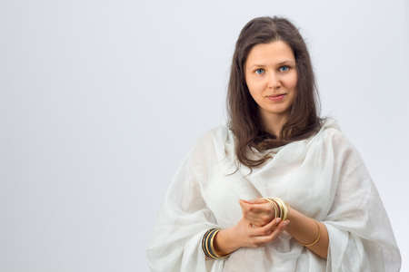 Portrait of a young woman with golden bracelets in a white backgroundの写真素材