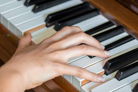 Close view of  girl's right hand finger holding pressed  keys on a pianoの写真素材