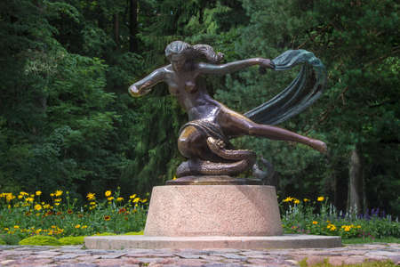 Girl's sculpture with grass-snake in a park in summerの写真素材