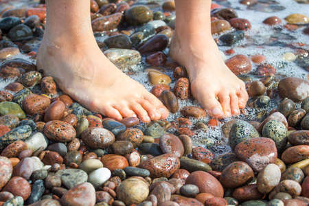 Close view of woman's foot on a beach stonesの写真素材