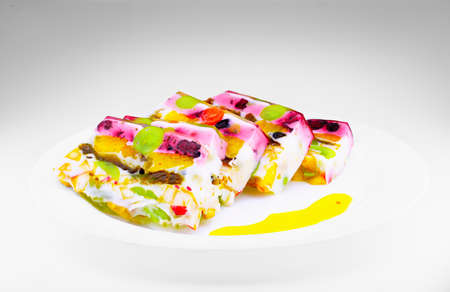 Pieces of jelly cake with fruits and milk in a white background