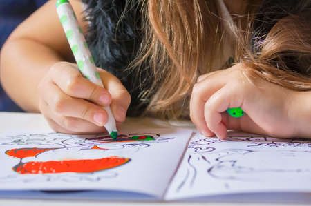 Close view of girls hands drawing on a paper with marker