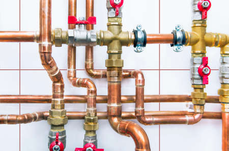 Heating system's cooper pipes with ball valves on a white wallの写真素材