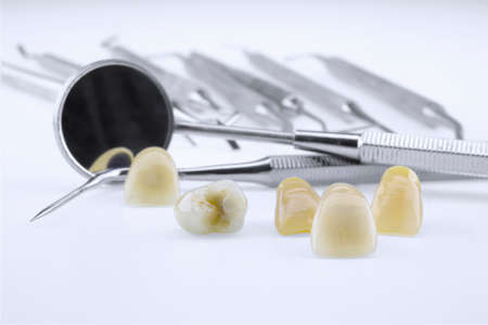 Metal ceramic dentures with dentist tools in a white background