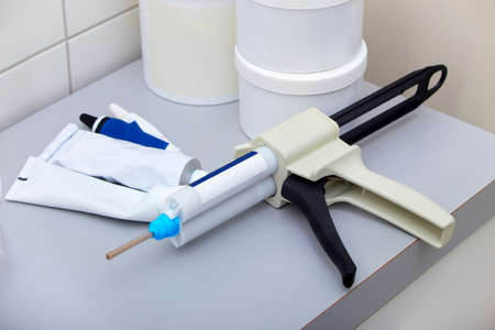 Dental dispensing gun with silicone tubes on a dentist tableの写真素材
