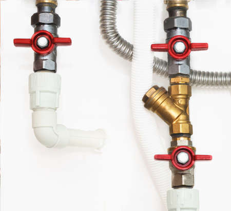 Heating system's plastic pipes with ball valves on a white wall
